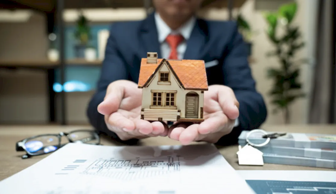 Игрушечный домик в руках банкира – символ ипотечного кредитования